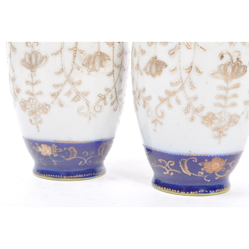 25 - A pair of Japanese china vases having white ground with dark blue borders and foliate decoration, wi... 