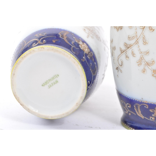 25 - A pair of Japanese china vases having white ground with dark blue borders and foliate decoration, wi... 