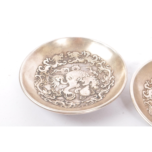 274 - A pair of Chinese Baitong metal plates. Each plate of rounded form with repousse dragon motifs to ce... 