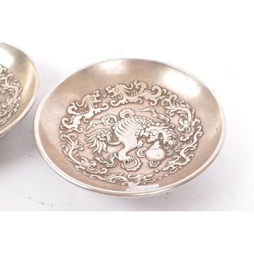 274 - A pair of Chinese Baitong metal plates. Each plate of rounded form with repousse dragon motifs to ce... 