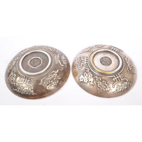 274 - A pair of Chinese Baitong metal plates. Each plate of rounded form with repousse dragon motifs to ce... 