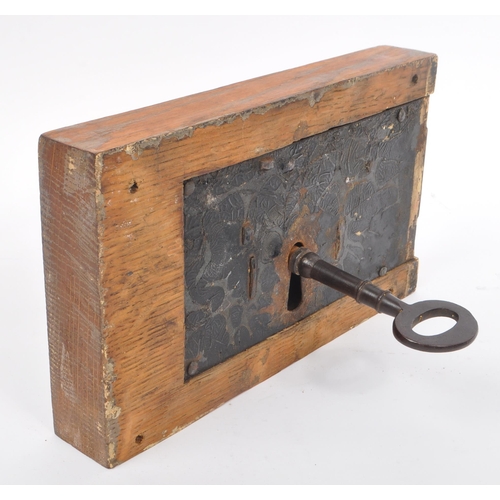 283 - A large 19th Century painted cast metal door lock having wooden block surround of rectangular form, ... 