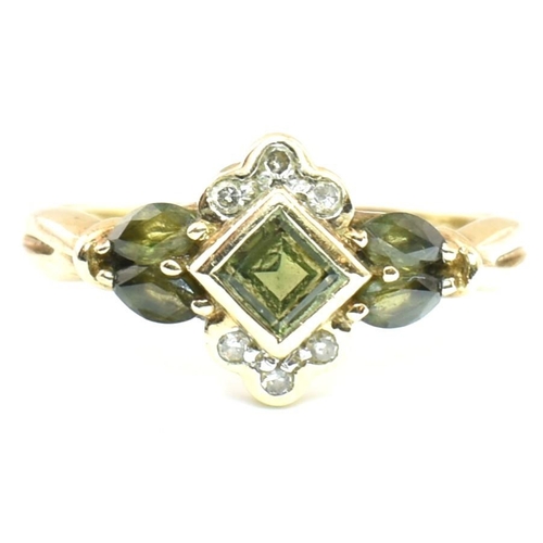 104 - A hallmarked 9ct gold, diamond and green sapphire cluster ring. The ring having a central bezel set ... 