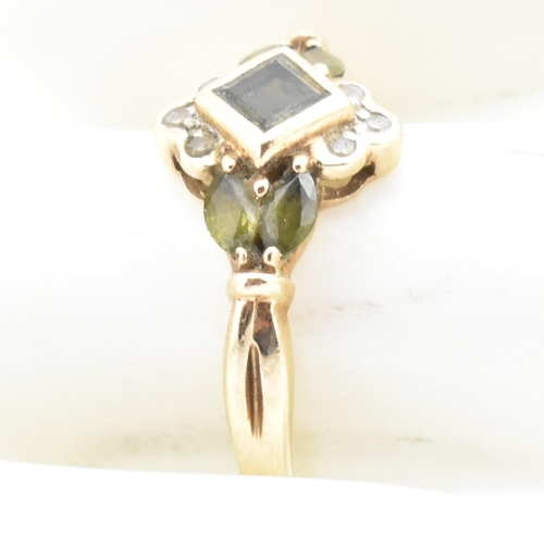 104 - A hallmarked 9ct gold, diamond and green sapphire cluster ring. The ring having a central bezel set ... 