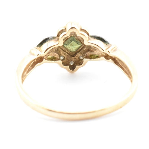 104 - A hallmarked 9ct gold, diamond and green sapphire cluster ring. The ring having a central bezel set ... 