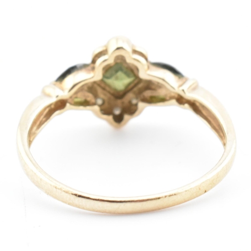 104 - A hallmarked 9ct gold, diamond and green sapphire cluster ring. The ring having a central bezel set ... 