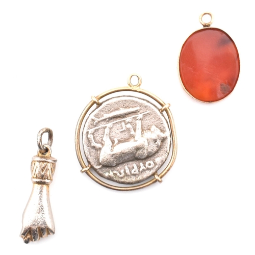 107 - Three necklace pendants. The pendants to include an oval carnelian pendant carved with stars and Ara... 