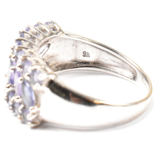 121 - A hallmarked 9ct white gold and purple stone cluster ring. The ring having central row of six marqui... 