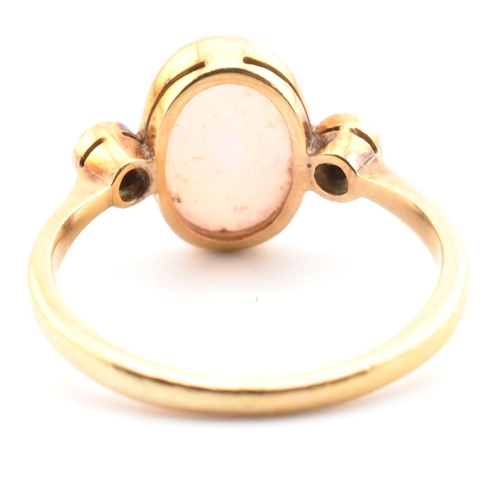 17 - An Edwardian 18ct gold opal and diamond three stone ring. The ring set with an oval cut opal cabocho... 