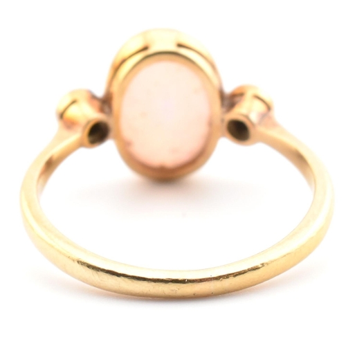 17 - An Edwardian 18ct gold opal and diamond three stone ring. The ring set with an oval cut opal cabocho... 