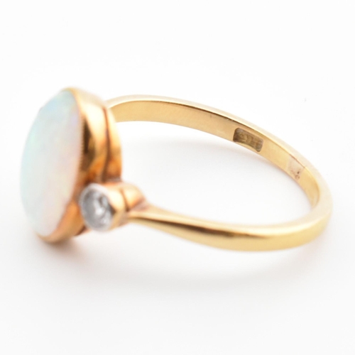 17 - An Edwardian 18ct gold opal and diamond three stone ring. The ring set with an oval cut opal cabocho... 