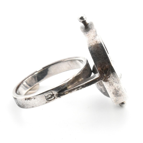 24 - A mid-century modernist 800 silver ring. The ring having a roundel top with articulating cup to plai... 