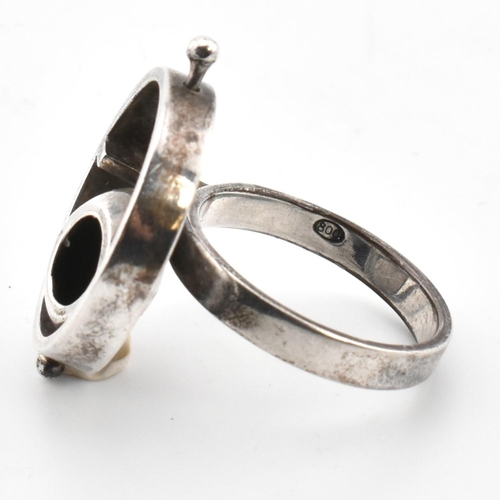 24 - A mid-century modernist 800 silver ring. The ring having a roundel top with articulating cup to plai... 