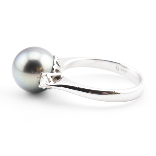 32 - An 18ct white gold, Tahitian pearl and diamond three stone ring. The 18ct white gold ring having a c... 