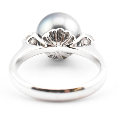 32 - An 18ct white gold, Tahitian pearl and diamond three stone ring. The 18ct white gold ring having a c... 