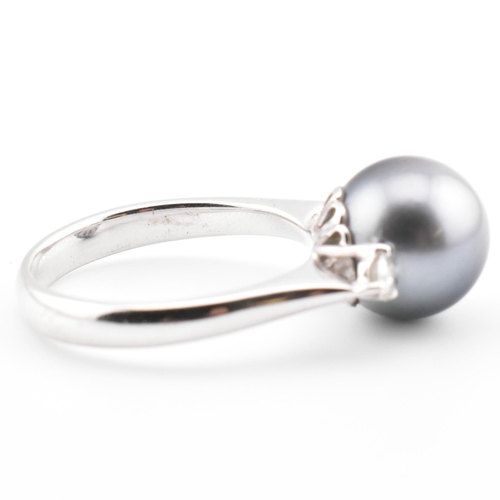 32 - An 18ct white gold, Tahitian pearl and diamond three stone ring. The 18ct white gold ring having a c... 