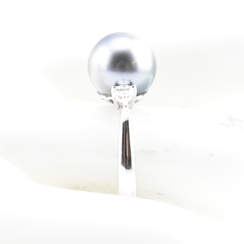 32 - An 18ct white gold, Tahitian pearl and diamond three stone ring. The 18ct white gold ring having a c... 