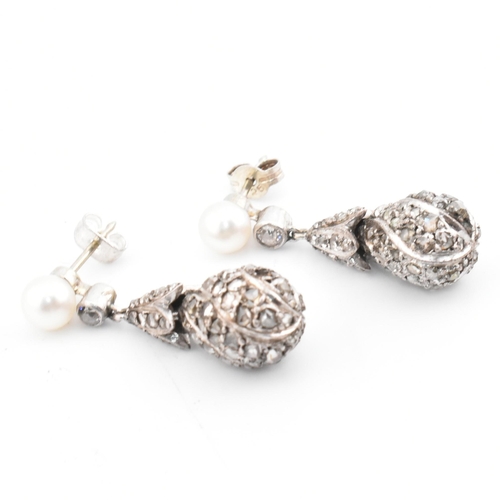 33 - A pair of pearl and diamond pendant earrings. The pendant earrings having a pave diamond set drop su... 