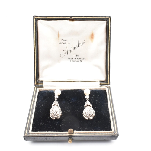 33 - A pair of pearl and diamond pendant earrings. The pendant earrings having a pave diamond set drop su... 