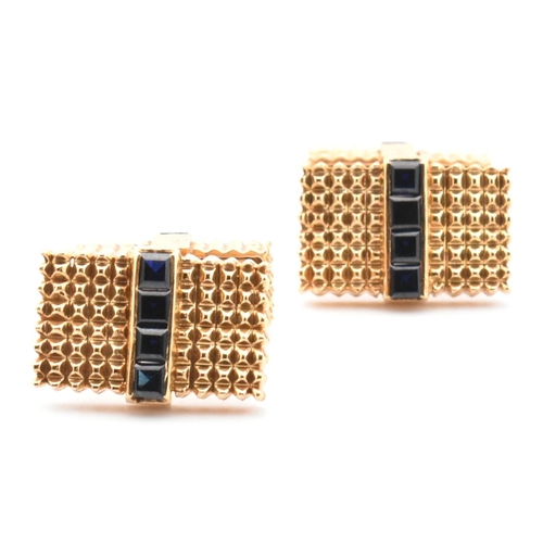 46 - A pair of synthetic sapphire set cufflinks. The cufflinks having rectangular faces with spiked decor... 