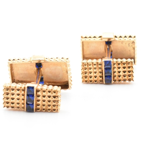 46 - A pair of synthetic sapphire set cufflinks. The cufflinks having rectangular faces with spiked decor... 