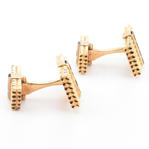 46 - A pair of synthetic sapphire set cufflinks. The cufflinks having rectangular faces with spiked decor... 