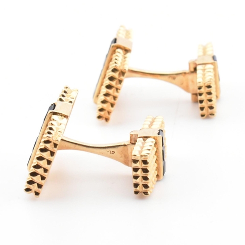 46 - A pair of synthetic sapphire set cufflinks. The cufflinks having rectangular faces with spiked decor... 