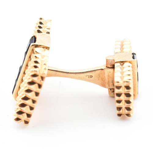 46 - A pair of synthetic sapphire set cufflinks. The cufflinks having rectangular faces with spiked decor... 