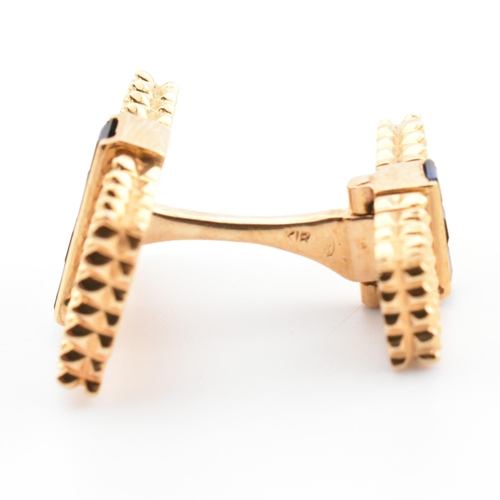 46 - A pair of synthetic sapphire set cufflinks. The cufflinks having rectangular faces with spiked decor... 