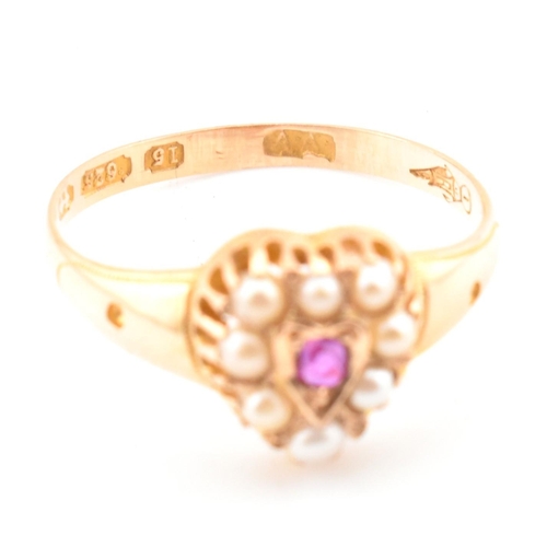 55 - A Victorian hallmarked 15ct gold, ruby and pearl heart ring. The ring set with a central round cut r... 