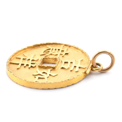 56 - An 18ct gold Chinese coin necklace pendant. The 18ct yellow gold pierced coin pendant having four Ch... 