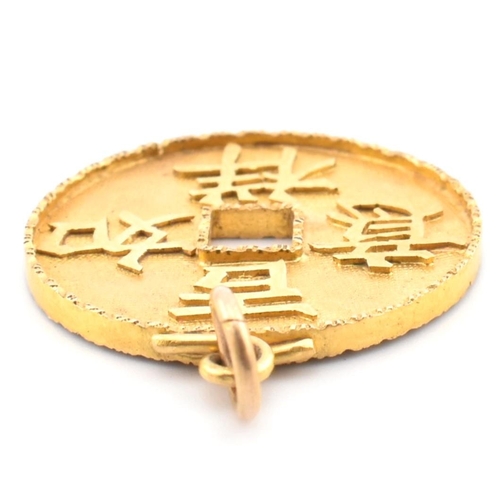 56 - An 18ct gold Chinese coin necklace pendant. The 18ct yellow gold pierced coin pendant having four Ch... 