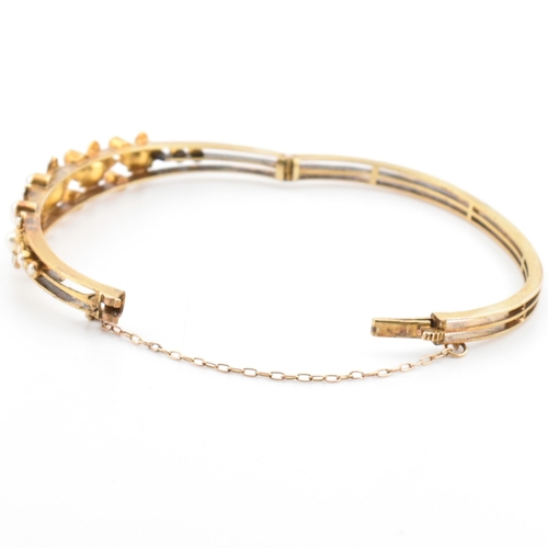 7 - An antique 15ct gold and pearl hinged bangle. The yellow gold hinged bangle having five graduating g... 