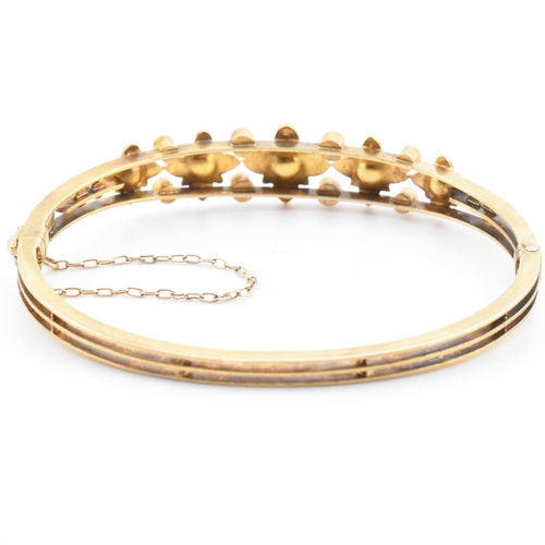 7 - An antique 15ct gold and pearl hinged bangle. The yellow gold hinged bangle having five graduating g... 