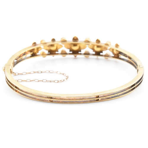 7 - An antique 15ct gold and pearl hinged bangle. The yellow gold hinged bangle having five graduating g... 