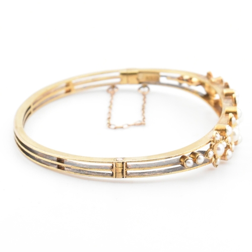 7 - An antique 15ct gold and pearl hinged bangle. The yellow gold hinged bangle having five graduating g... 