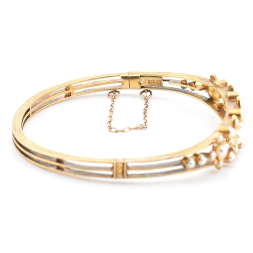 7 - An antique 15ct gold and pearl hinged bangle. The yellow gold hinged bangle having five graduating g... 