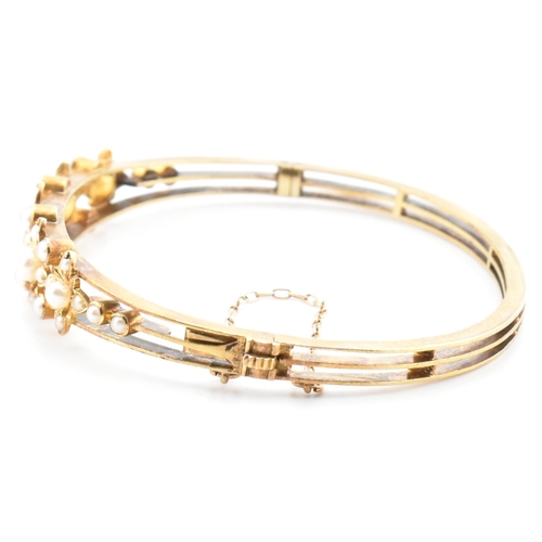 7 - An antique 15ct gold and pearl hinged bangle. The yellow gold hinged bangle having five graduating g... 