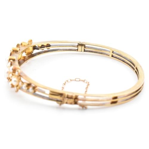 7 - An antique 15ct gold and pearl hinged bangle. The yellow gold hinged bangle having five graduating g... 