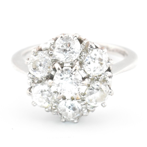 70 - A platinum and diamond seven stone cluster ring. The ring set with seven round cut diamonds in a clu... 