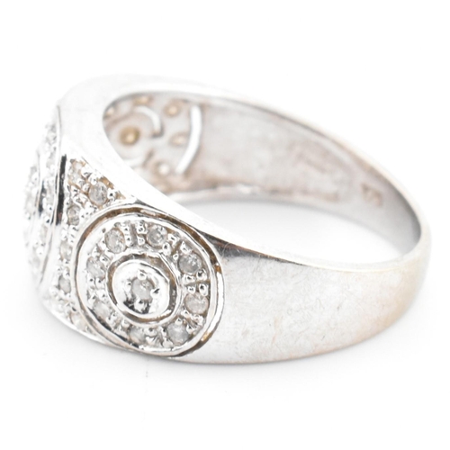 74 - A hallmarked 9ct white gold and diamond ring. The 9ct white gold domed ring having three circles set... 