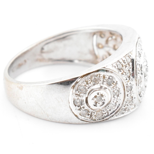 74 - A hallmarked 9ct white gold and diamond ring. The 9ct white gold domed ring having three circles set... 