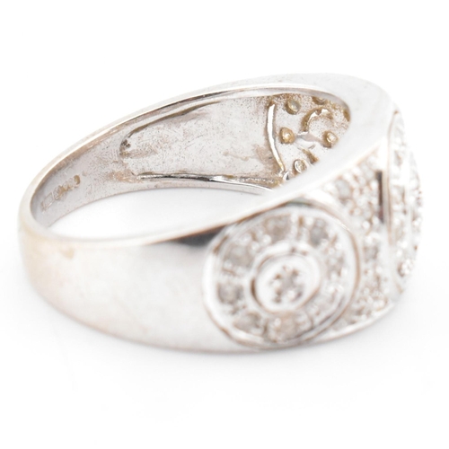 74 - A hallmarked 9ct white gold and diamond ring. The 9ct white gold domed ring having three circles set... 