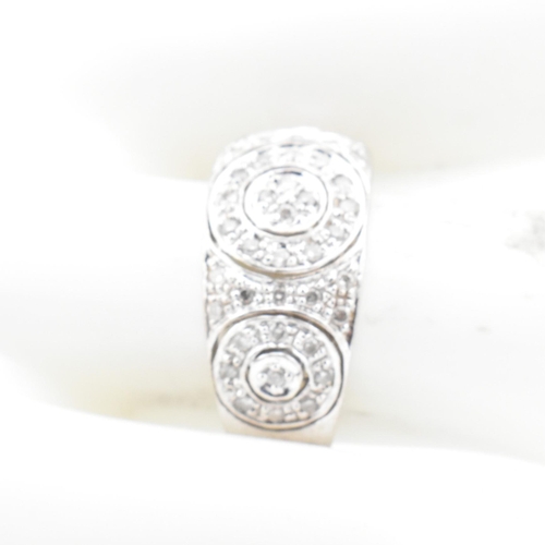 74 - A hallmarked 9ct white gold and diamond ring. The 9ct white gold domed ring having three circles set... 