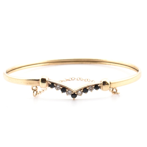 78 - A hallmarked 9ct gold, CZ and sapphire wishbone bangle. The 9ct gold bangle wishbone bangle having a... 