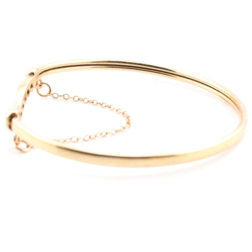 78 - A hallmarked 9ct gold, CZ and sapphire wishbone bangle. The 9ct gold bangle wishbone bangle having a... 