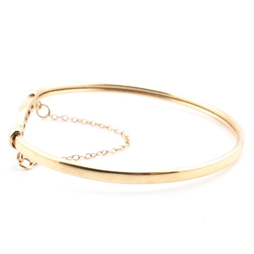 78 - A hallmarked 9ct gold, CZ and sapphire wishbone bangle. The 9ct gold bangle wishbone bangle having a... 