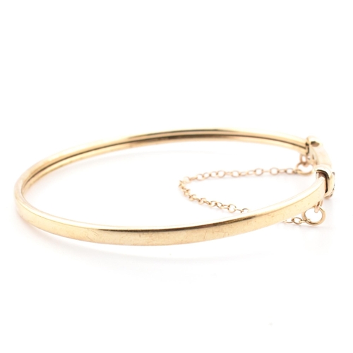 78 - A hallmarked 9ct gold, CZ and sapphire wishbone bangle. The 9ct gold bangle wishbone bangle having a... 