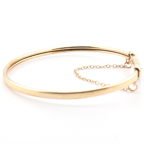 78 - A hallmarked 9ct gold, CZ and sapphire wishbone bangle. The 9ct gold bangle wishbone bangle having a... 