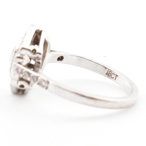 80 - An 18ct white gold and diamond Art Deco ring. The ring set with a central round cut diamond flanked ... 